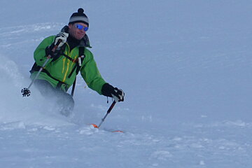 a skier in a green jacket in the snow