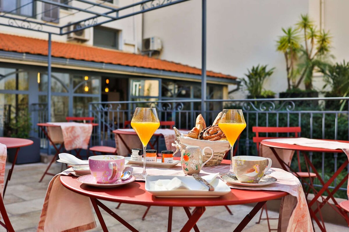 A table with a basket of bread and two glasses of orange juice