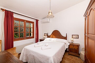 A bedroom with a bed and a window with red curtains