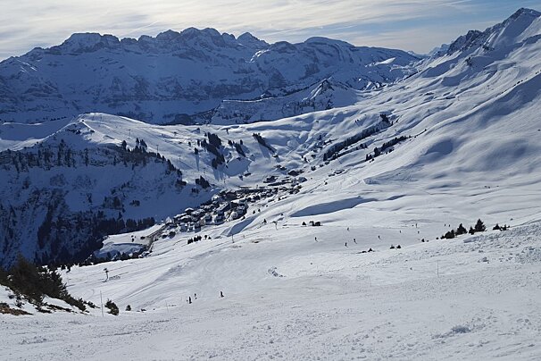 A snowy mountain with a ski slope in the foreground