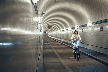 A woman is riding a bike through a tunnel
