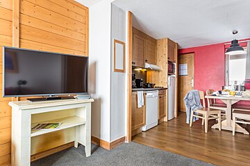 A flat screen tv sits on a shelf in a kitchen