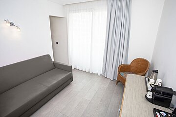 A hotel room with a couch and wicker chair