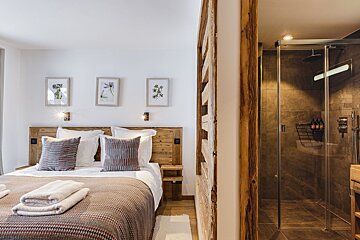 A bedroom with a large bed and a walk in shower