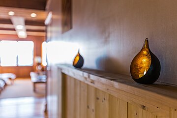 A candle holder sits on a wooden shelf in a hallway