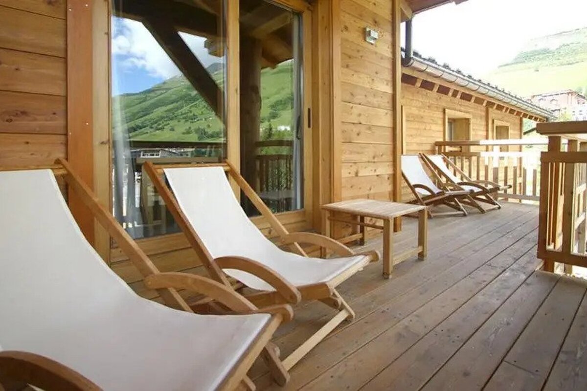 A wooden deck with lawn chairs and a table