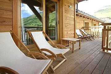 A wooden deck with lawn chairs and a table