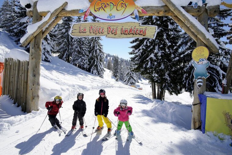 A group of children skiing under a sign that says la piste des indians