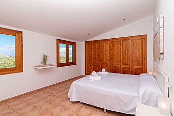 A bedroom with a king size bed and wooden cabinets