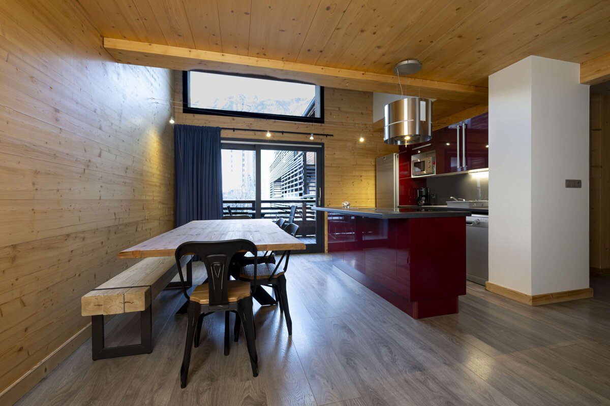 A kitchen with red cabinets and a wooden table