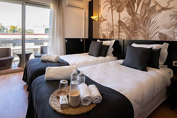 A hotel room with two beds and a tray of towels