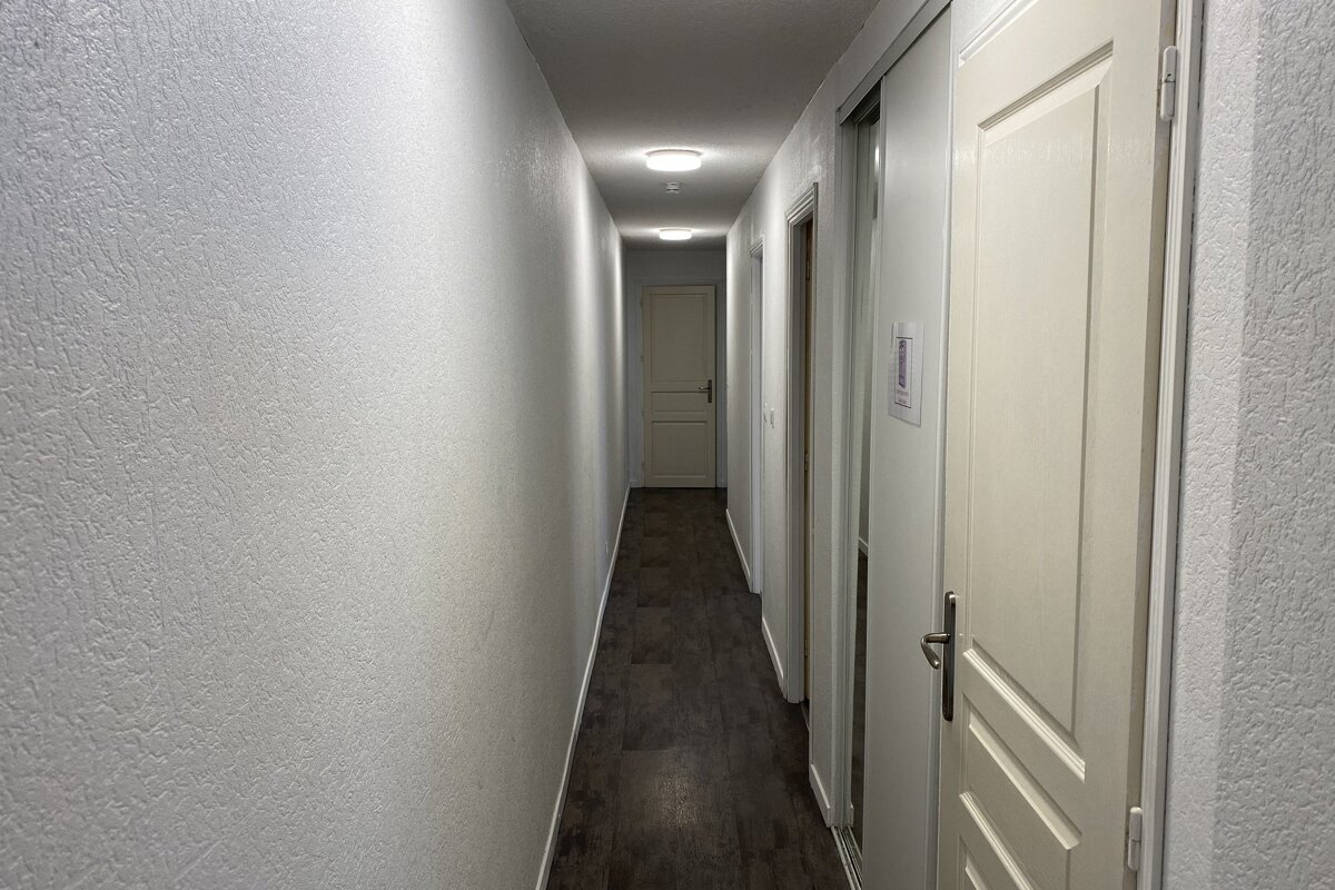 A hallway with a sign on the wall that says ' emergency exit '