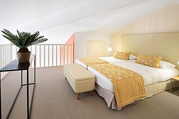 A bedroom with two beds and a plant on a table