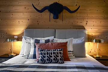 A bed with pillows on it and a horn hanging above it