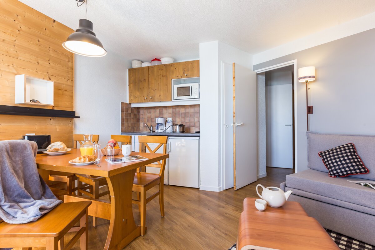A living room with a table and chairs and a kitchen