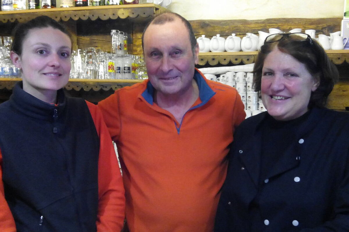 father, mother and daughter standing behind the bar