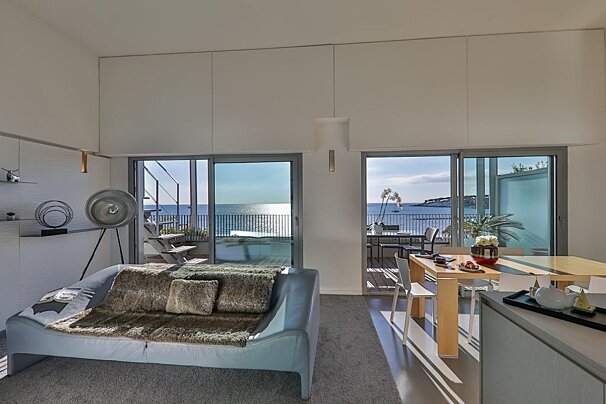 A living room with a couch and a table with a view of the ocean