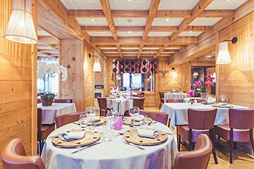 A dining room with tables and chairs and a wooden ceiling