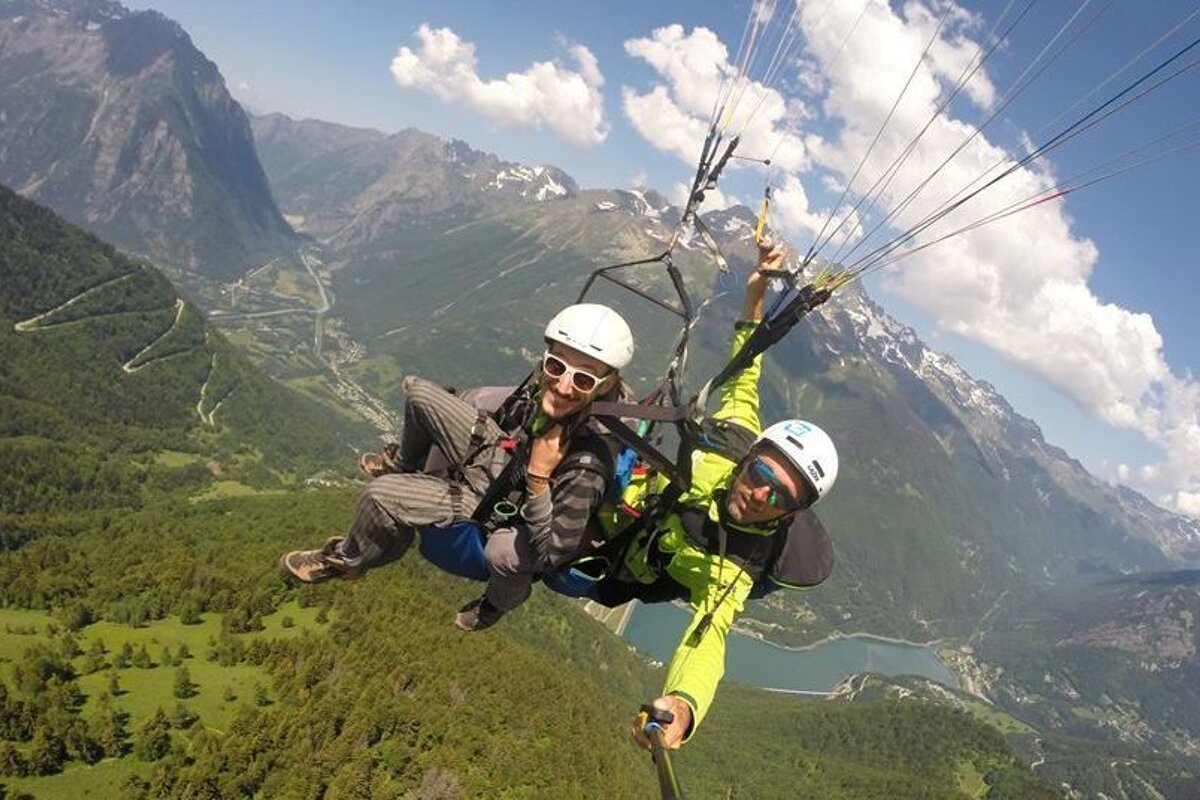A man and a woman are parasailing over a mountain range