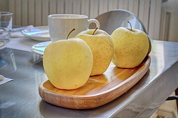 Three apples on a wooden tray on a table