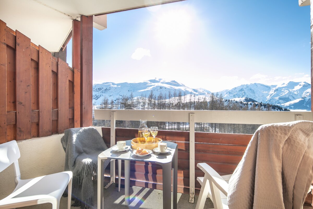 A balcony with a table and chairs and a view of the mountains