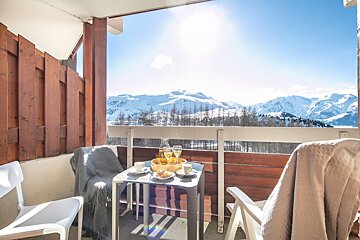A balcony with a table and chairs and a view of the mountains