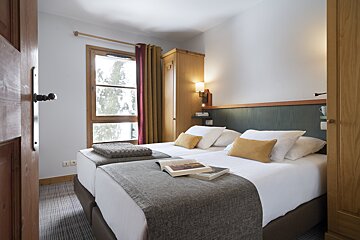A hotel room with two beds and a book on the bed