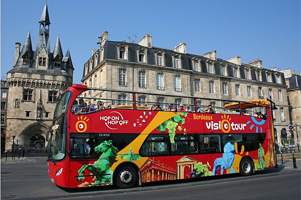 A double decker bus that says hop on hop off on the side
