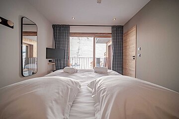 A bedroom with two beds and a television on the wall