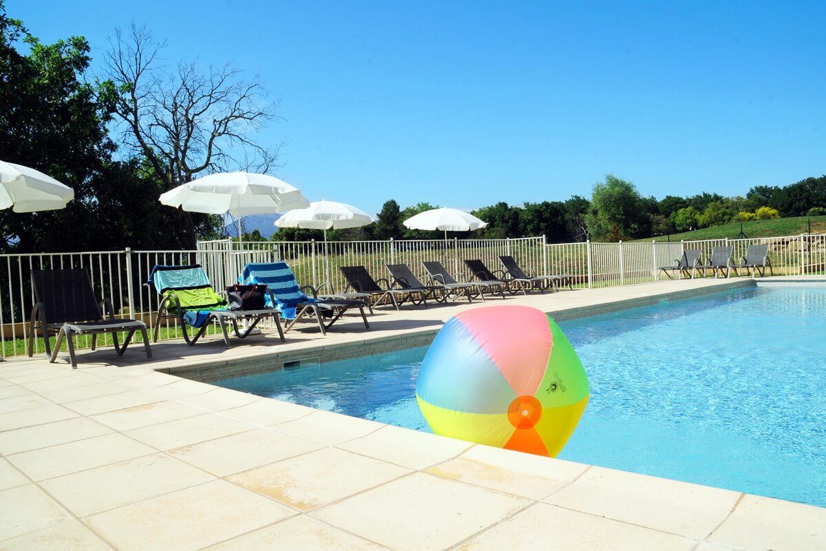 A colorful beach ball sits on the edge of a swimming pool