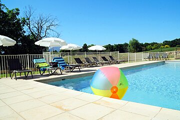 A colorful beach ball sits on the edge of a swimming pool