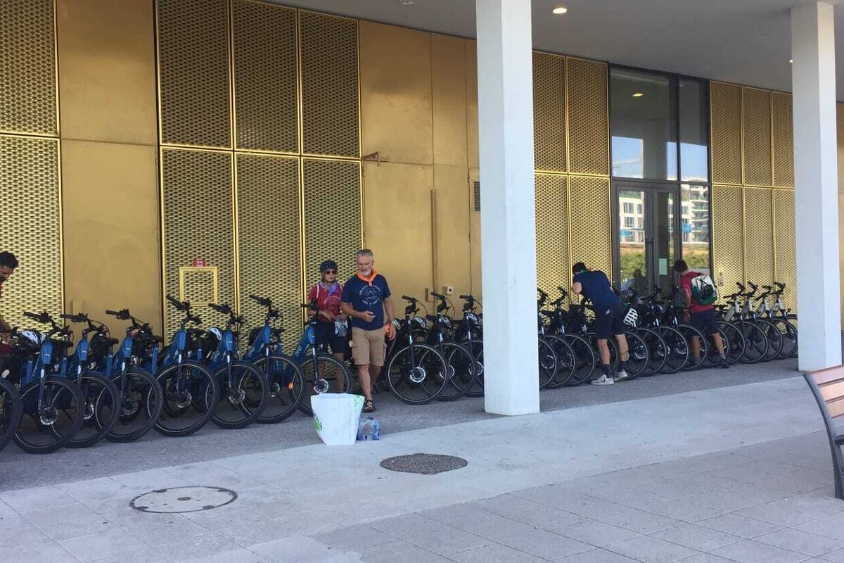 A man in a blue shirt stands in front of a row of bikes