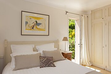 A framed picasso painting hangs above a bed