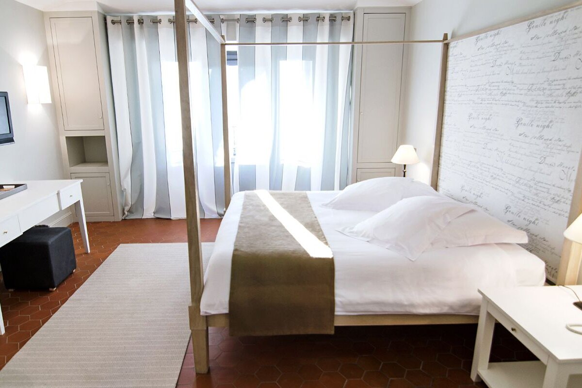 A bedroom with a four poster bed and a striped curtain
