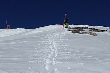 two ski tourers hiking up a snowy mountain