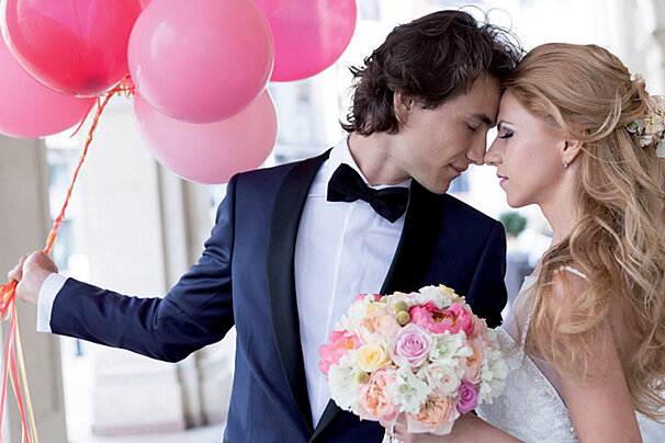 a bride & groom posing for a photo with pink ballons