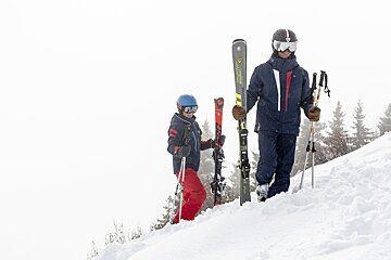 A man carrying a pair of skis that say rossignol on them