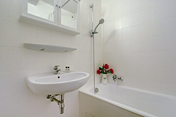 A white bathroom with a sink and a bathtub