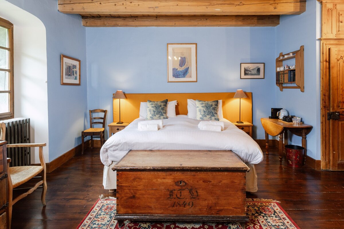 A bedroom with a bed and a trunk with the year 1840 on it