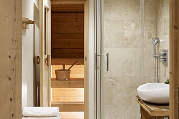 A bathroom with a wooden sauna and a white sink