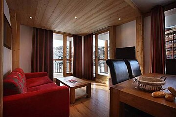 A living room with a red couch and a wooden table