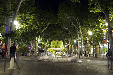 a fountain at night on a street in provence