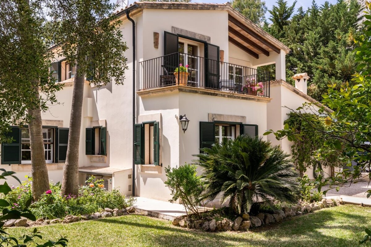 A white house with green shutters and a balcony