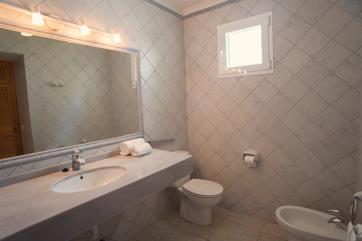 A bathroom with a sink toilet and bidet