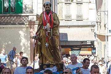 sailors carrying a statue of a saint through the streets of antibes