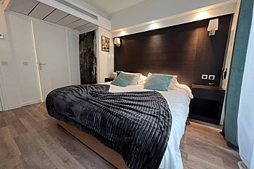 A hotel room with a bed with a blanket on it