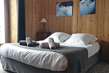 A bedroom with a bed and two paintings on the wall