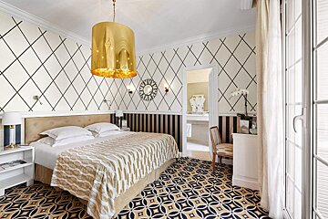A bedroom with a large bed and a gold lamp hanging from the ceiling