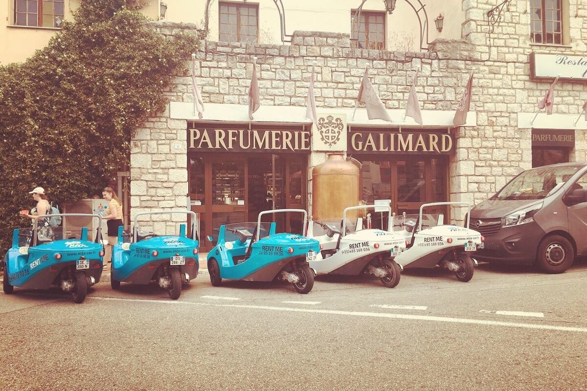 A row of vehicles are parked in front of a store called parfumerie galimard