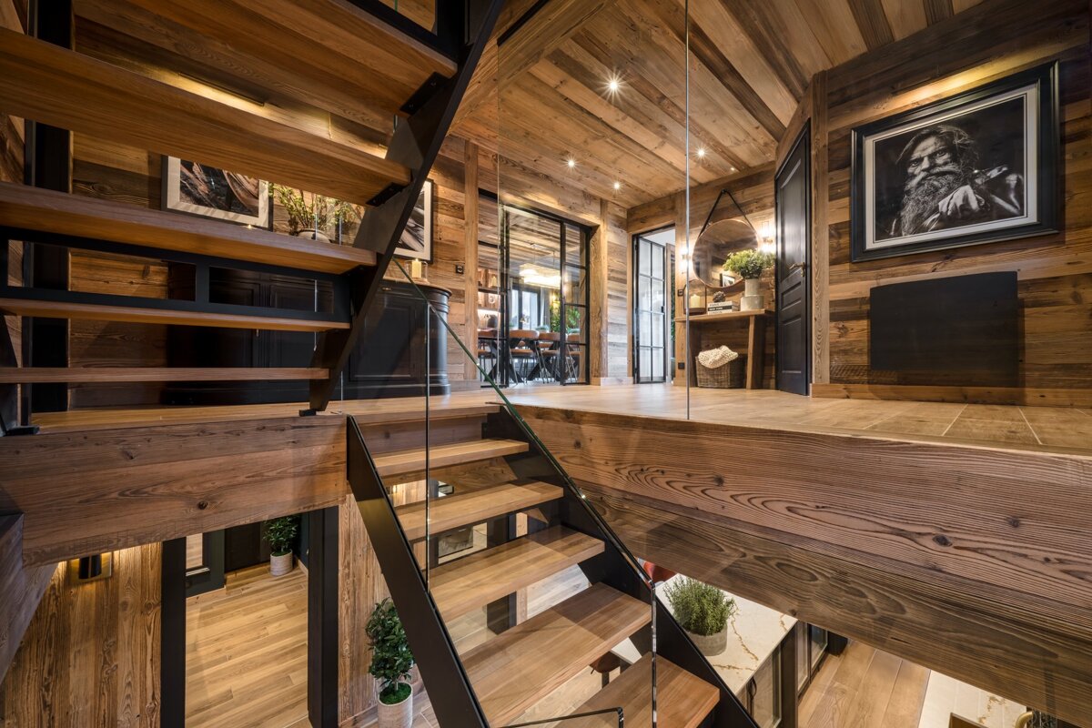 A wooden staircase with a glass railing and a picture of a man on the wall